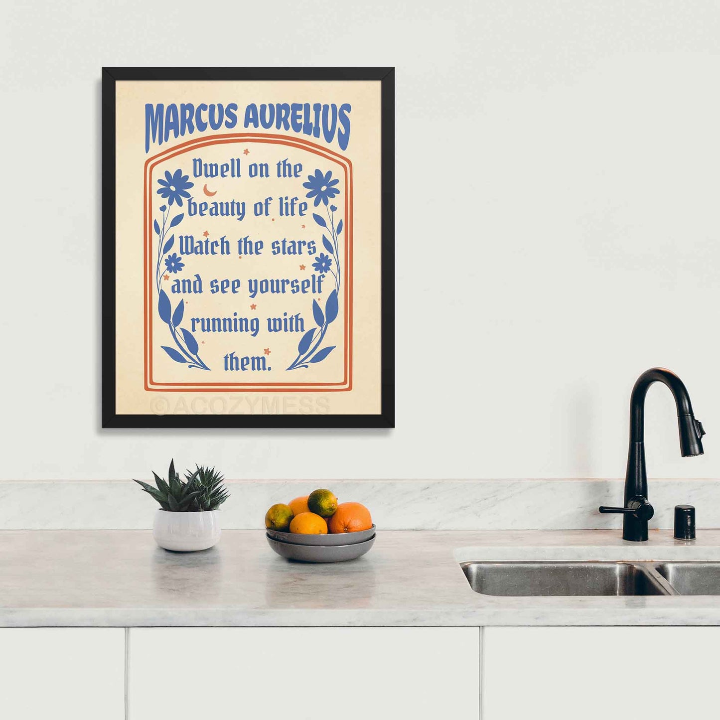 Stoic print displayed in black frame featuring the Marcus Aurelius quote, "Dwell on the beauty of life," in elegant typography on a kitchen wall.