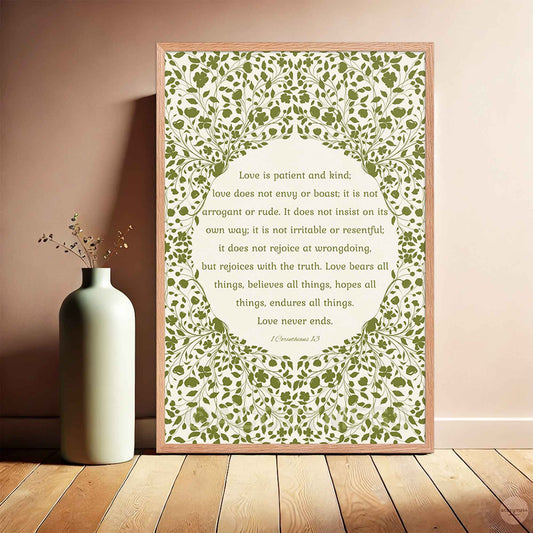 “Love is patient, love is kind” poster in a natural oakwood frame, featuring green floral artwork on a beige background—perfect for warm, rustic interiors.