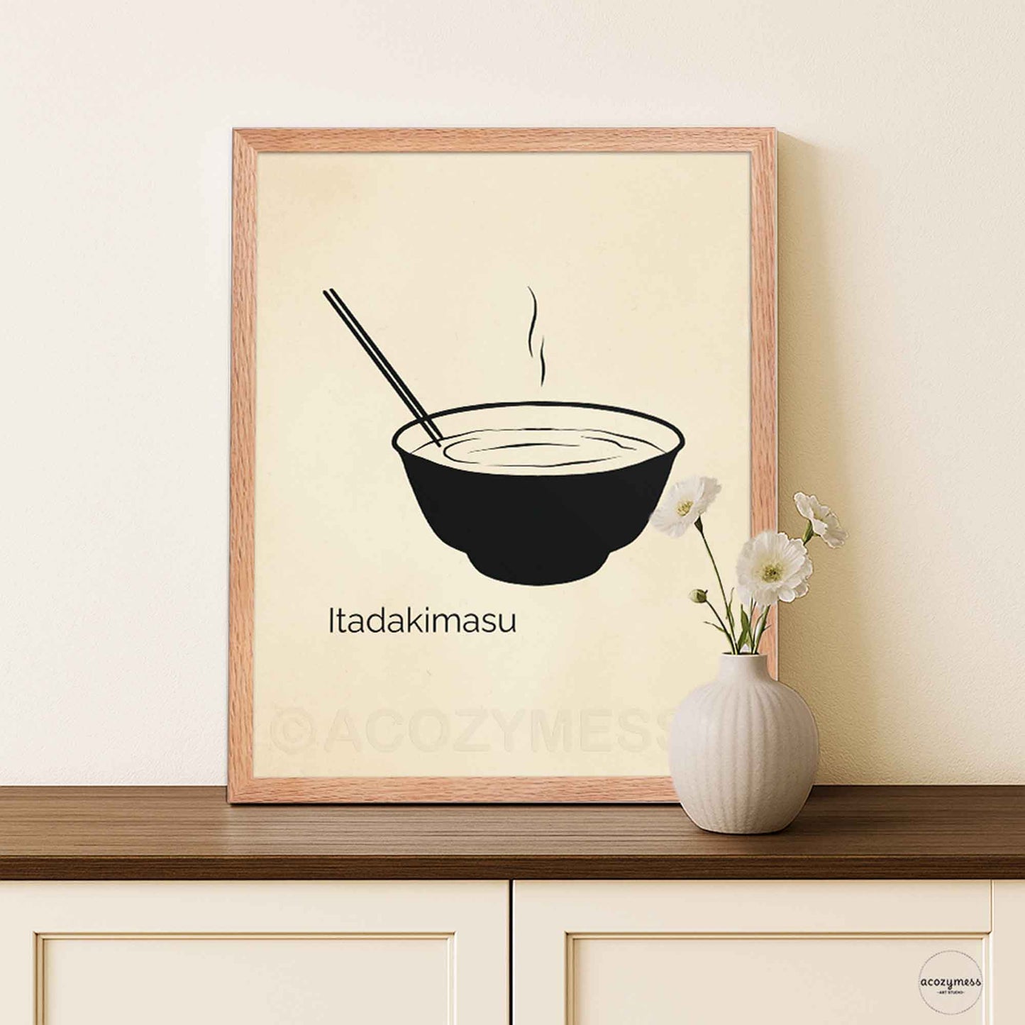 Framed artwork with a bowl and chopsticks on a beige background, featuring the text 'Itadakimasu'.