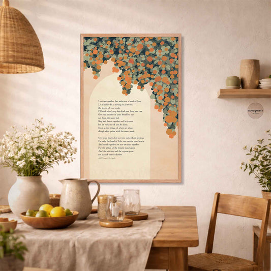 A framed art print featuring a Kahlil Gibran poem with a floral vine illustration, displayed on a wall in a warm, rustic dining room setting.