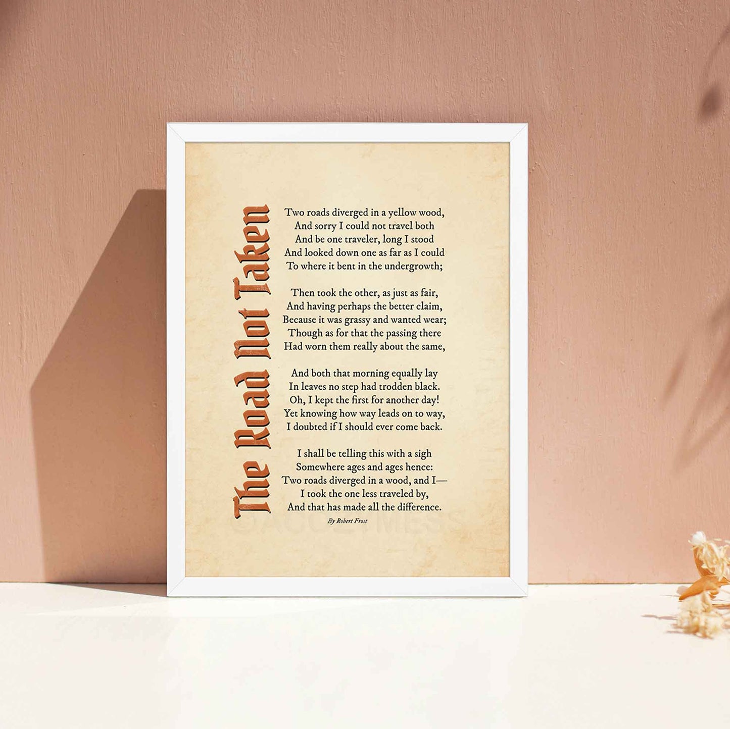 A vintage-style poem print featuring Robert Frost’s iconic poem, The Road Not Taken printed on an aged, old-paper background, in white frame.