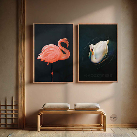 Two framed artworks of a flamingo and a swan on a wall above a wooden bench.