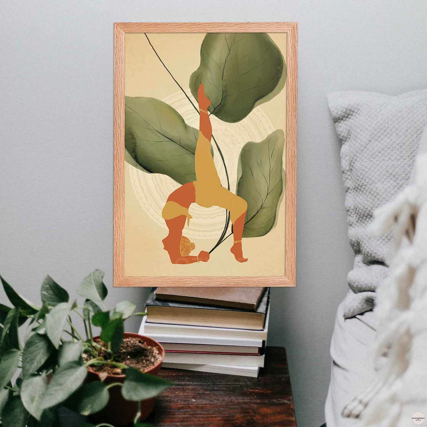 A oakwood-framed poster featuring an illustration of a woman in a yoga pose, set against a backdrop of large leafy plants and mandala art in earthy tones for calming corner decor.