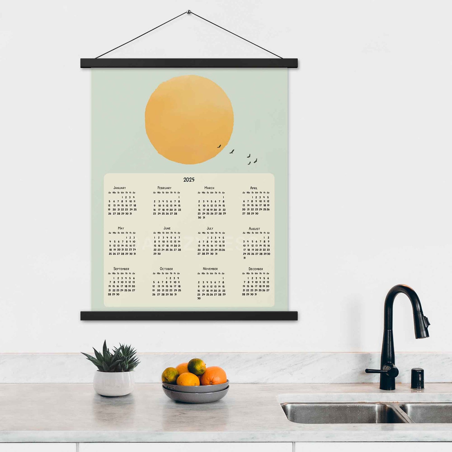 2025 yearly calendar poster featuring a sun illustration in a blue sky with flying birds,  with oak hanger on a kitchen wall.