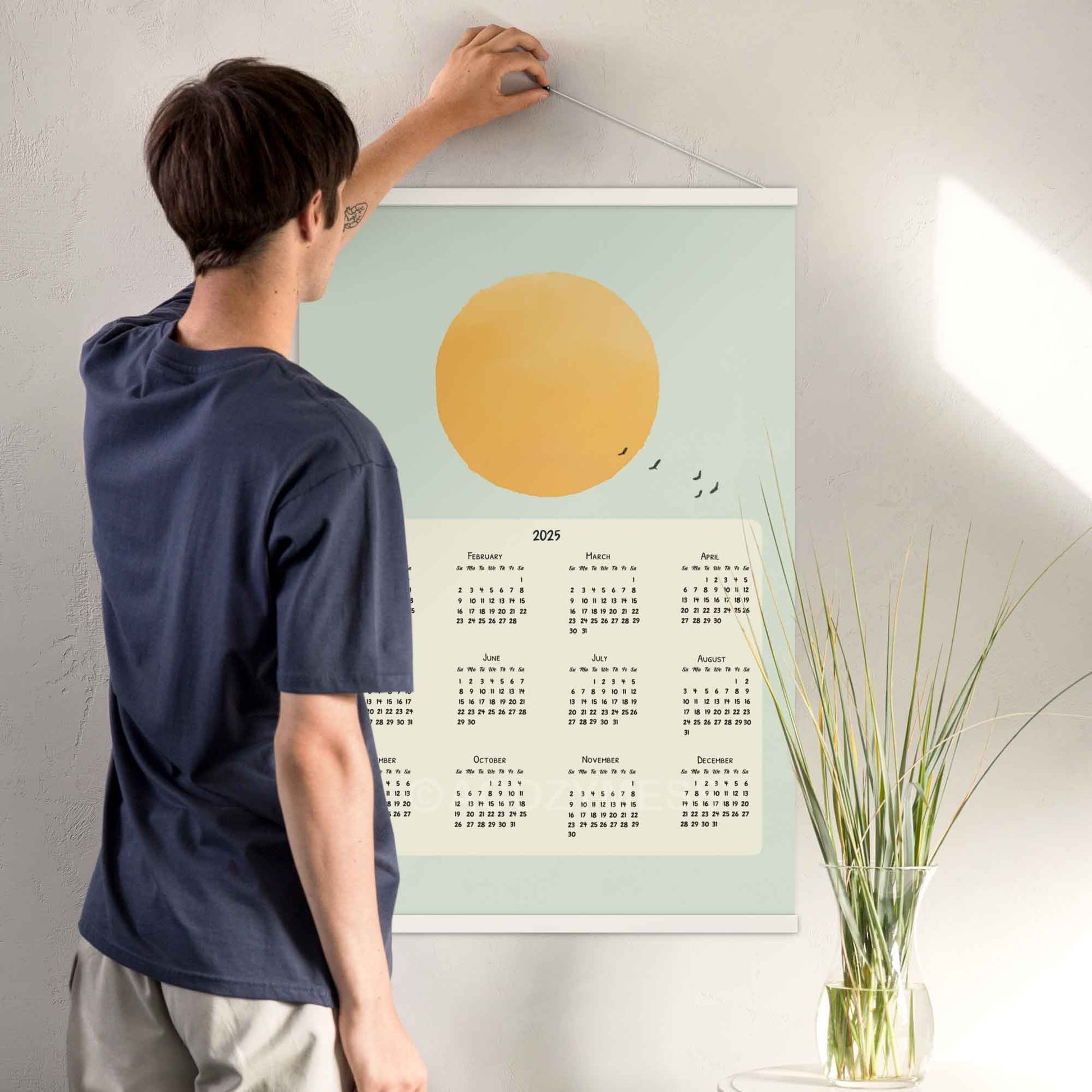 2025 yearly calendar poster featuring a sun illustration in a blue sky with flying birds,  with white hanger.