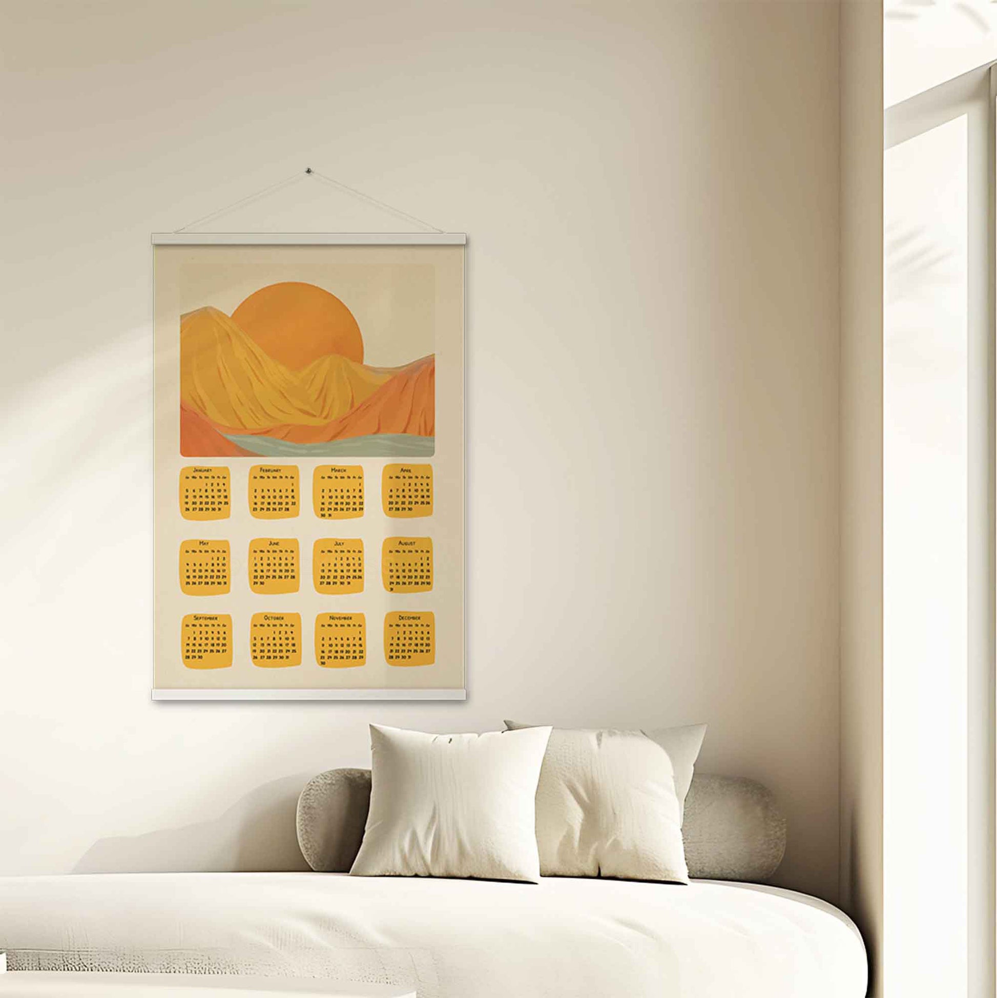 2025 illustrated calendar featuring a serene nature scene in yellow and orange tones, displayed with an white hanger on a entryway wall, perfect for adding warmth and charm.