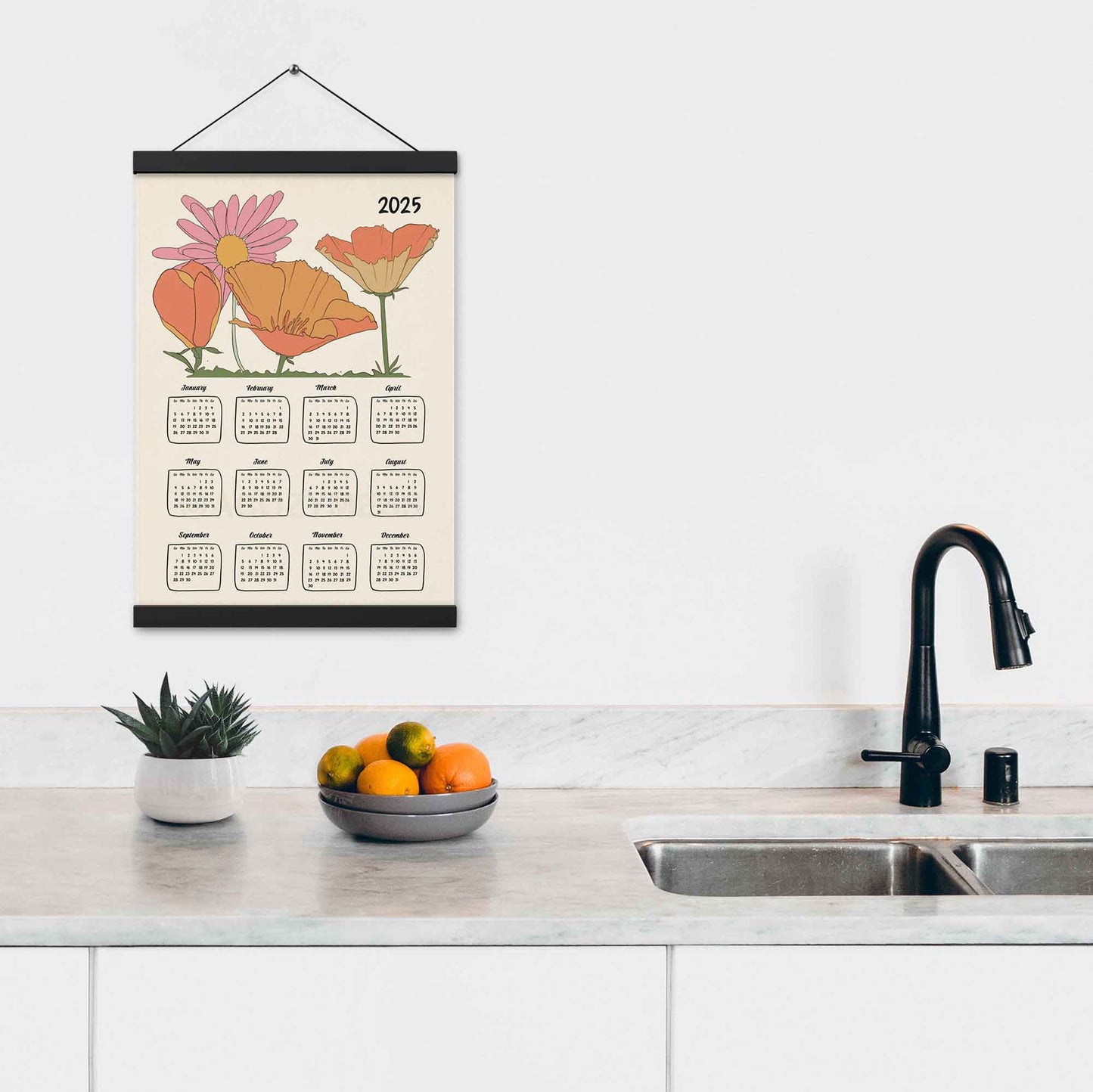 2025 yearly calendar poster with an illustrated floral design, with black  hanger on a kitchen wall.