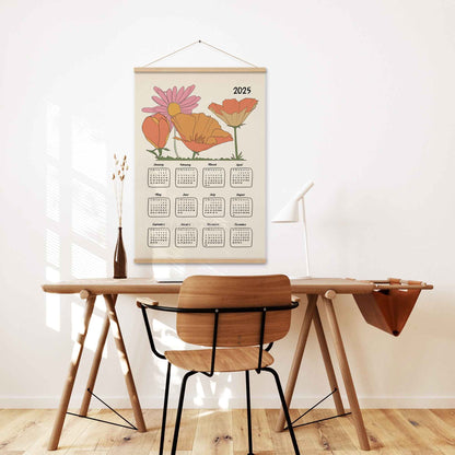 2025 yearly calendar poster with an illustrated floral design, with oakwood  hanger on a home office wall.