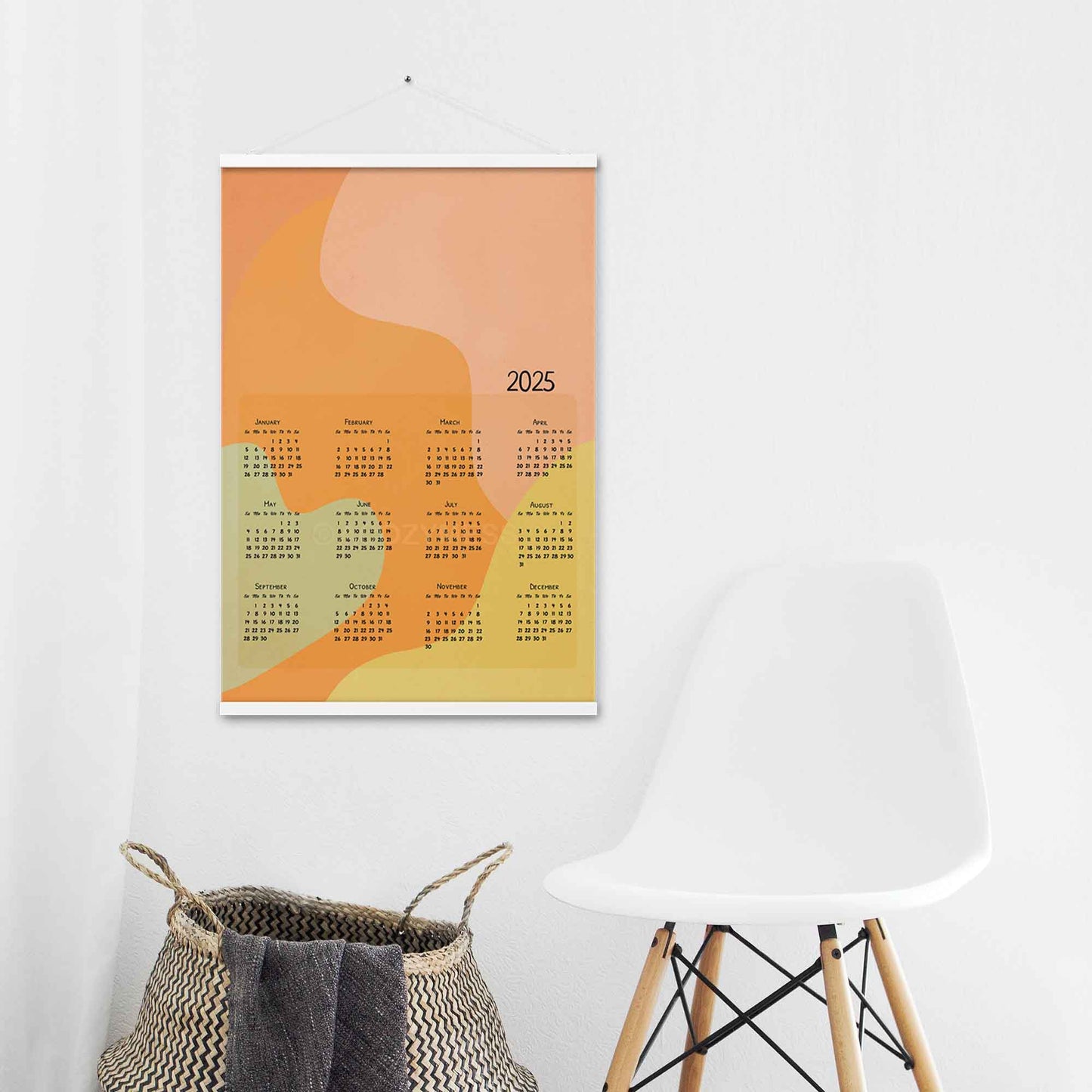 2025 yearly calendar poster with an abstract design in pastel colors, displayed with an white hanger on a laundry room wall.