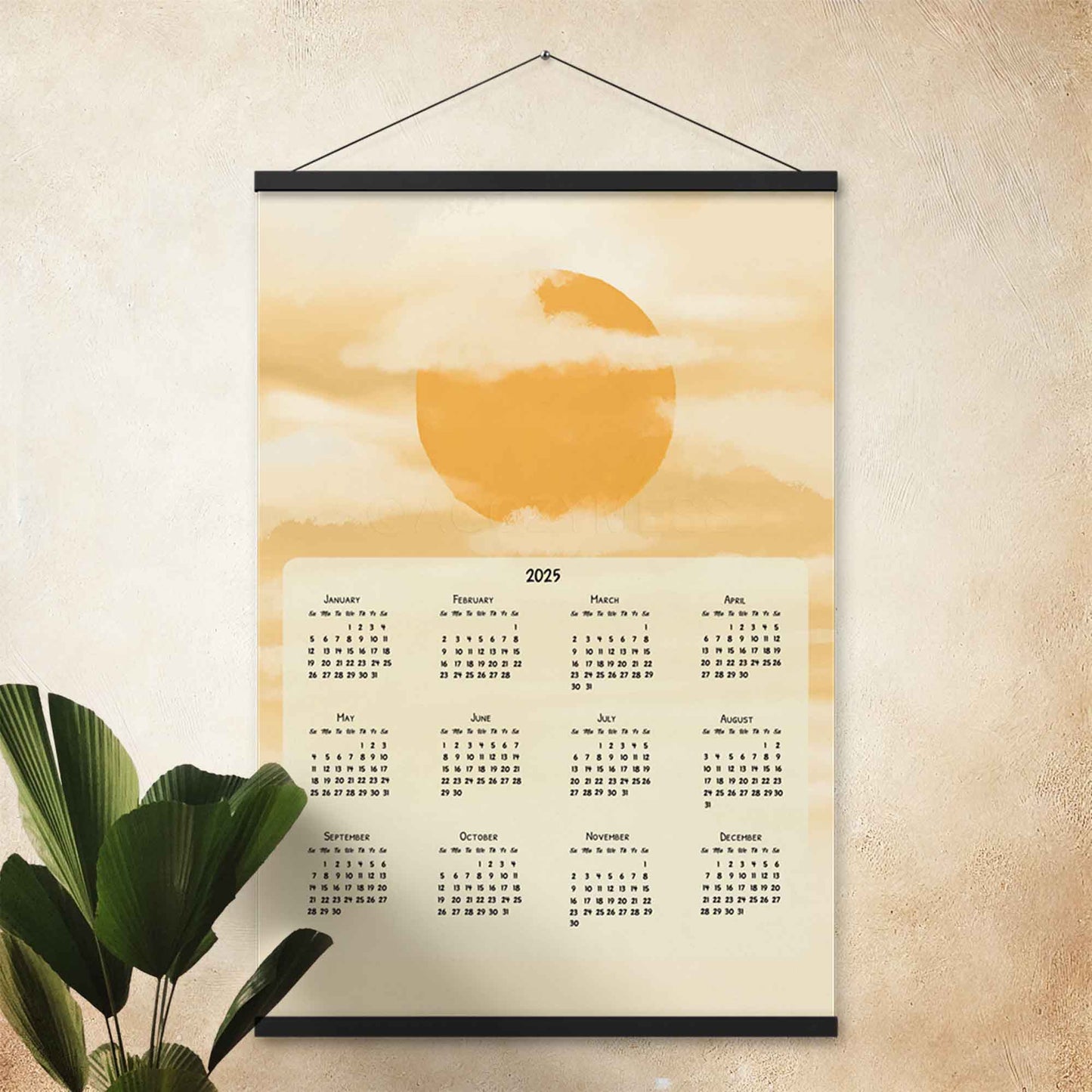 2025 yearly wall calendar featuring a sun and clouds illustration on a muted yellow background, adding warmth to the design, displayed in a black hanger frame on an office wall.