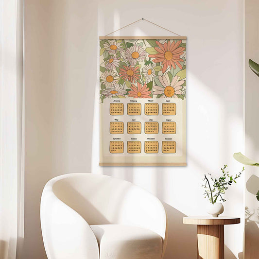 Illustrated 2025 calendar with floral design in beige, green, pink, and orange colors, featuring an oakwood hanger. 