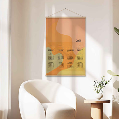 2025 yearly calendar poster with an abstract design in pastel colors, displayed with an wood hanger on a living room wall.