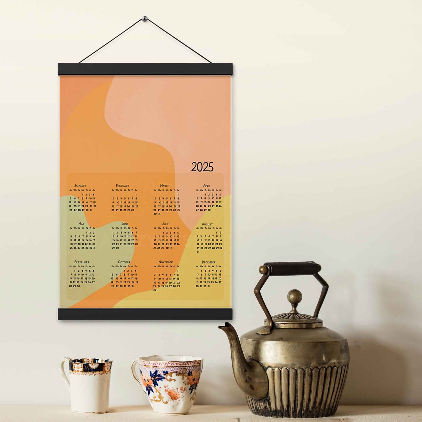 2025 yearly calendar poster with an abstract design in muted pastel colors, displayed with an wood hanger on a kitchen wall.