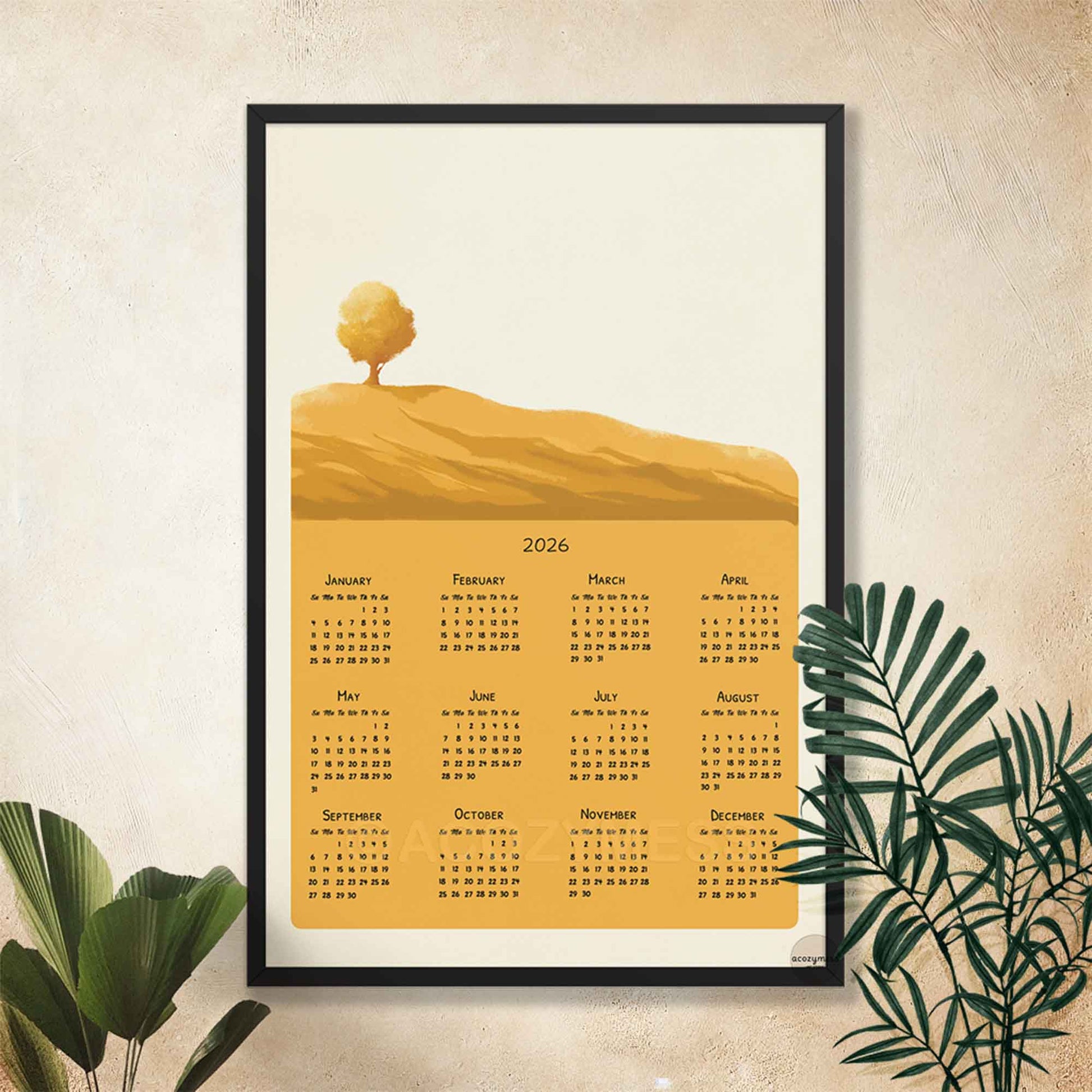 Framed 2026 calendar with a landscape design featuring a tree on a hill, displayed on a wall.