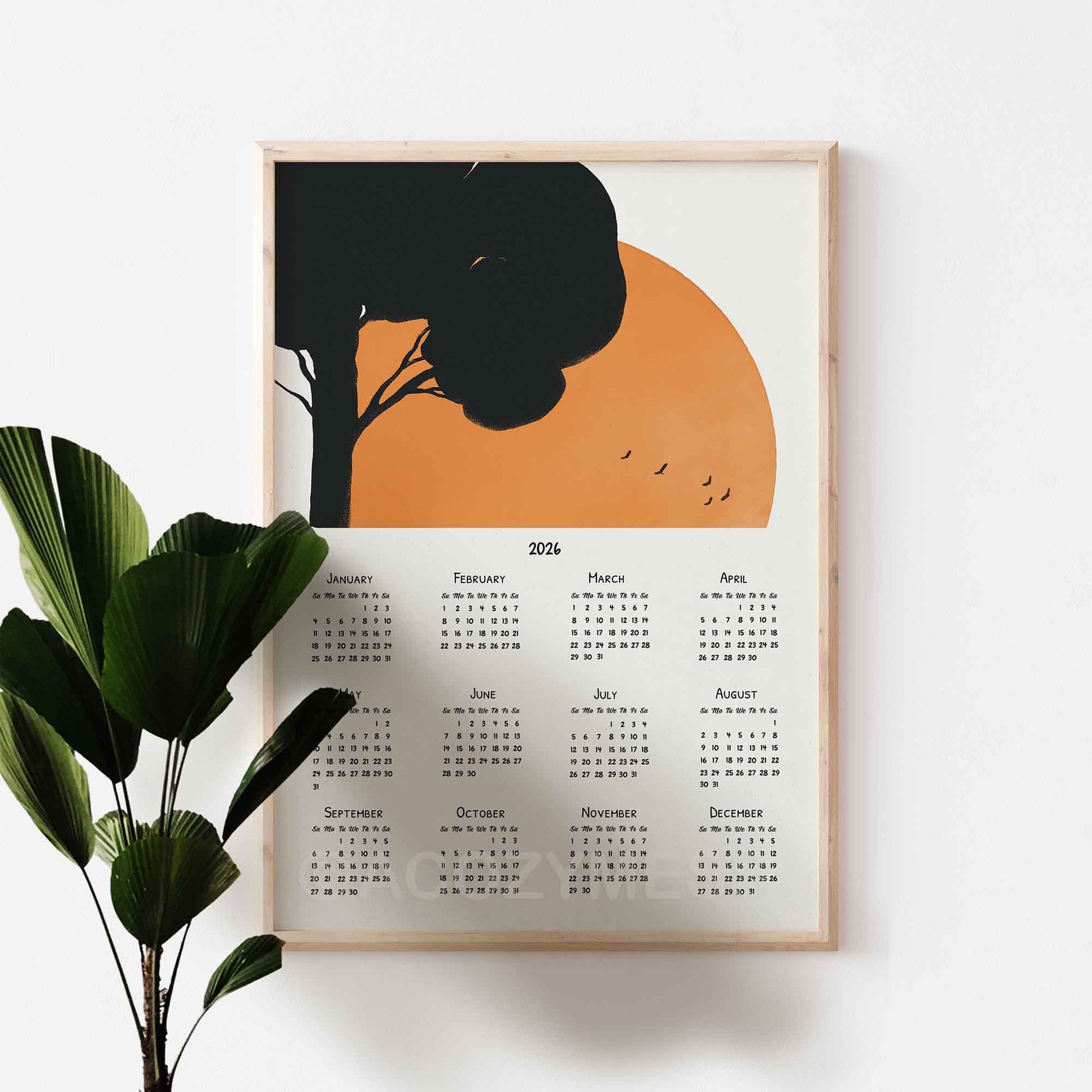 Framed  2026 calendar with tree and sunset design on a white wall