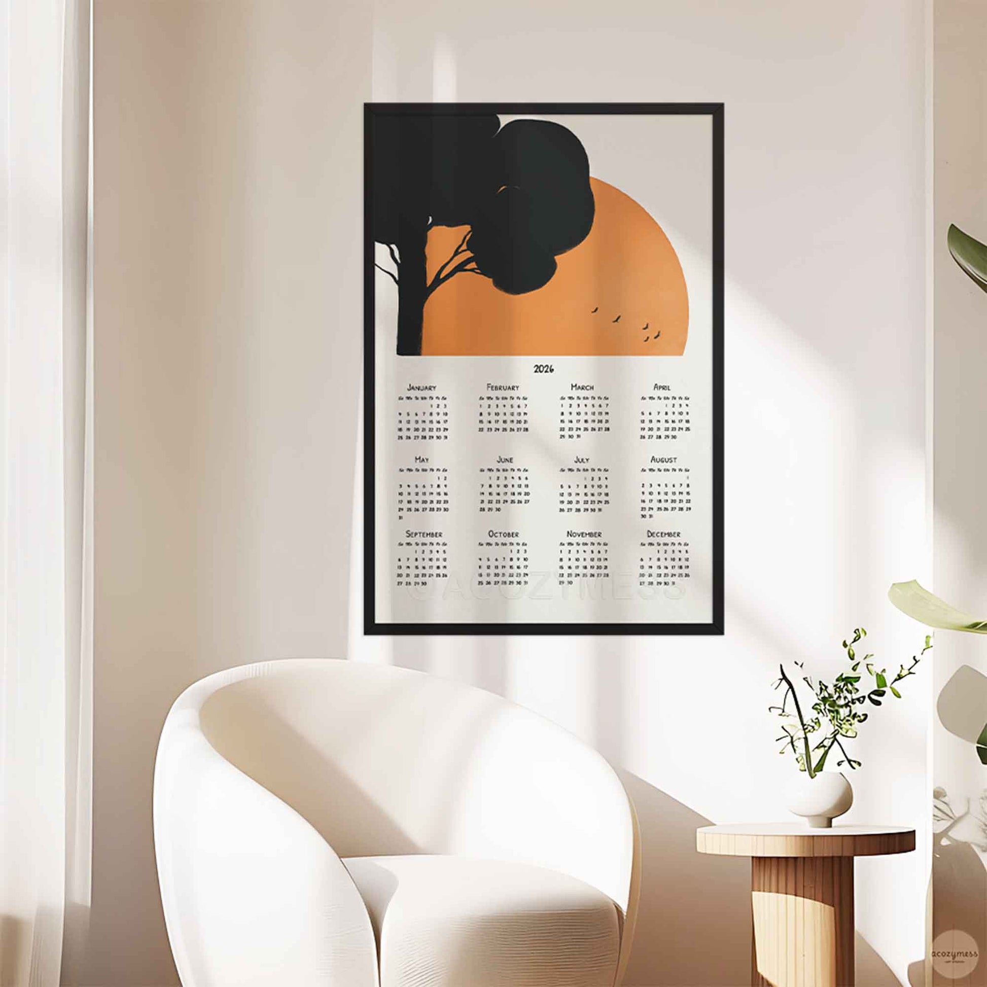 Framed calendar with tree and sun design on a wall.