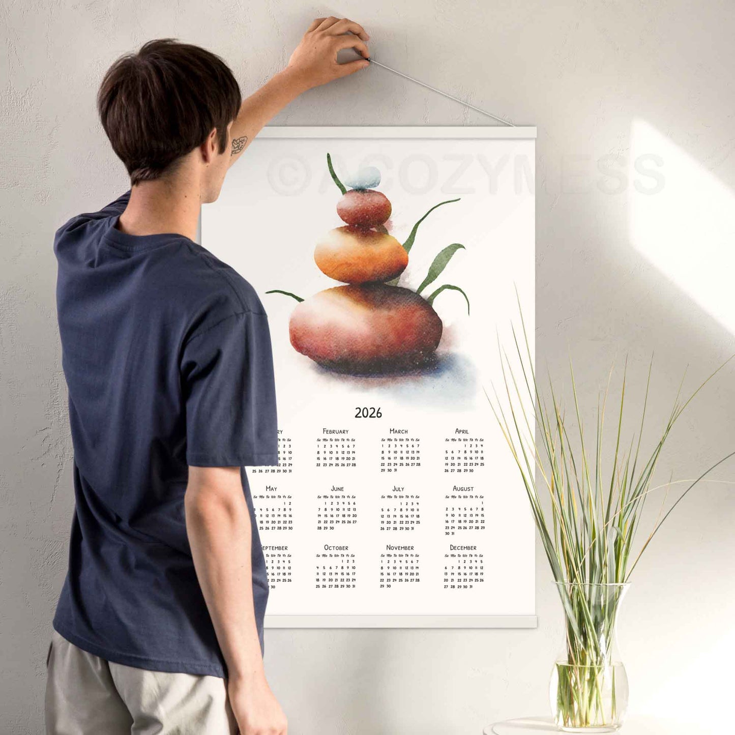  Wall calendar 2026 with balancing stones art hanging on a wall.