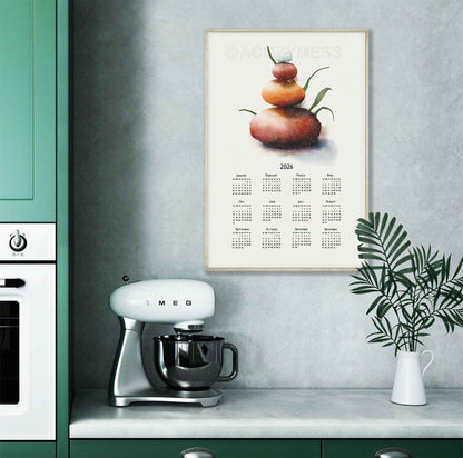 2026 calendar with balancing stones art displayed in wooden frame displayed on a kitchen wall.