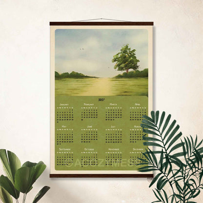 2027 green meadow calendar poster in a dark wooden hanger frame on a cream wall with palm leaves