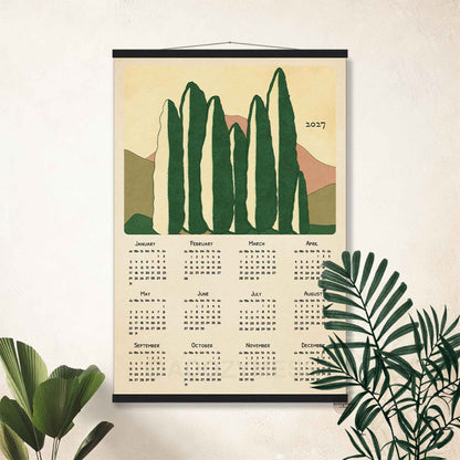 2027 cypress trees calendar poster in a black hanger frame on a white wall with palm leaves