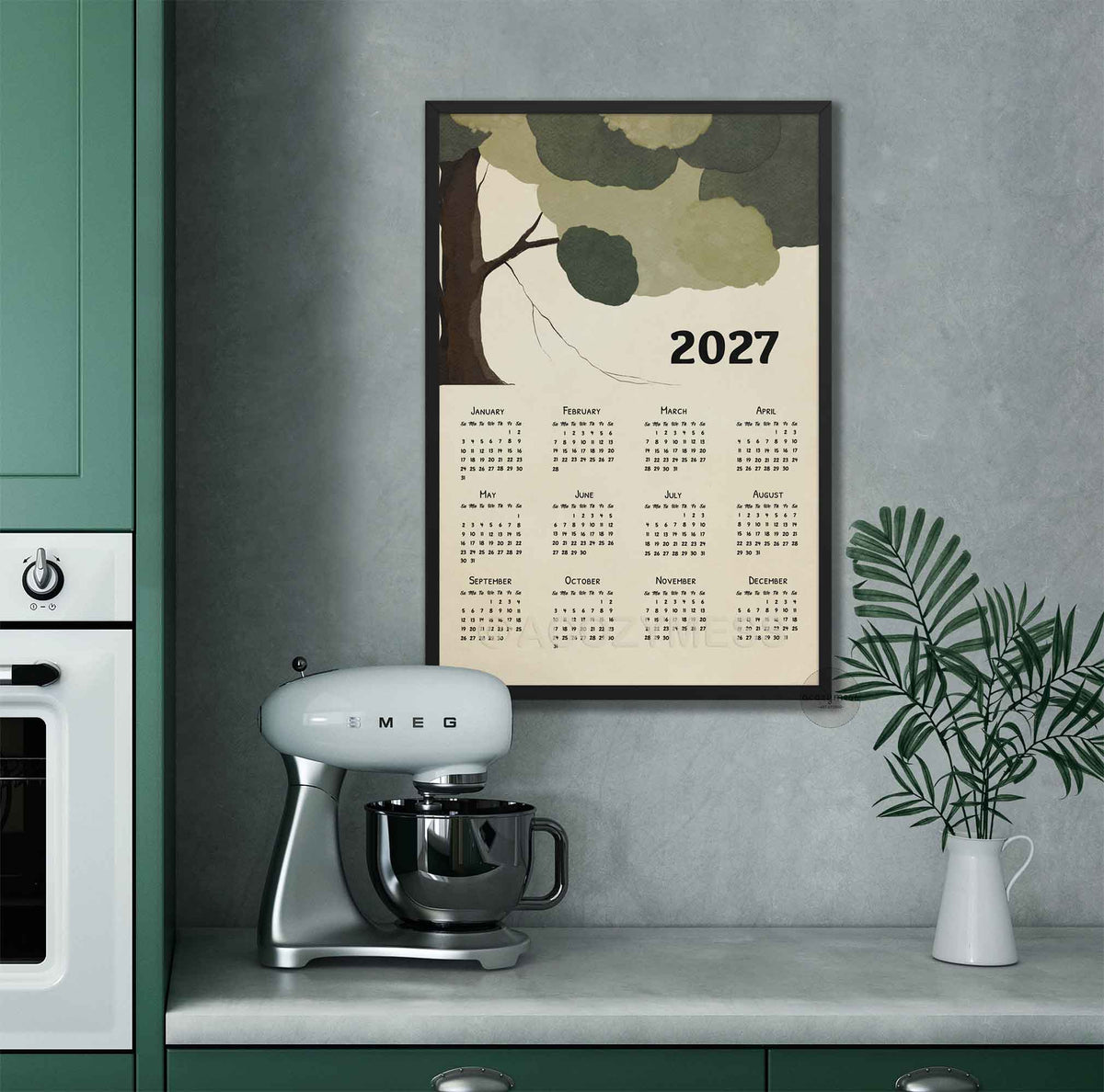 Black framed 2027 tree calendar poster on a gray kitchen wall above a stand mixer and plant