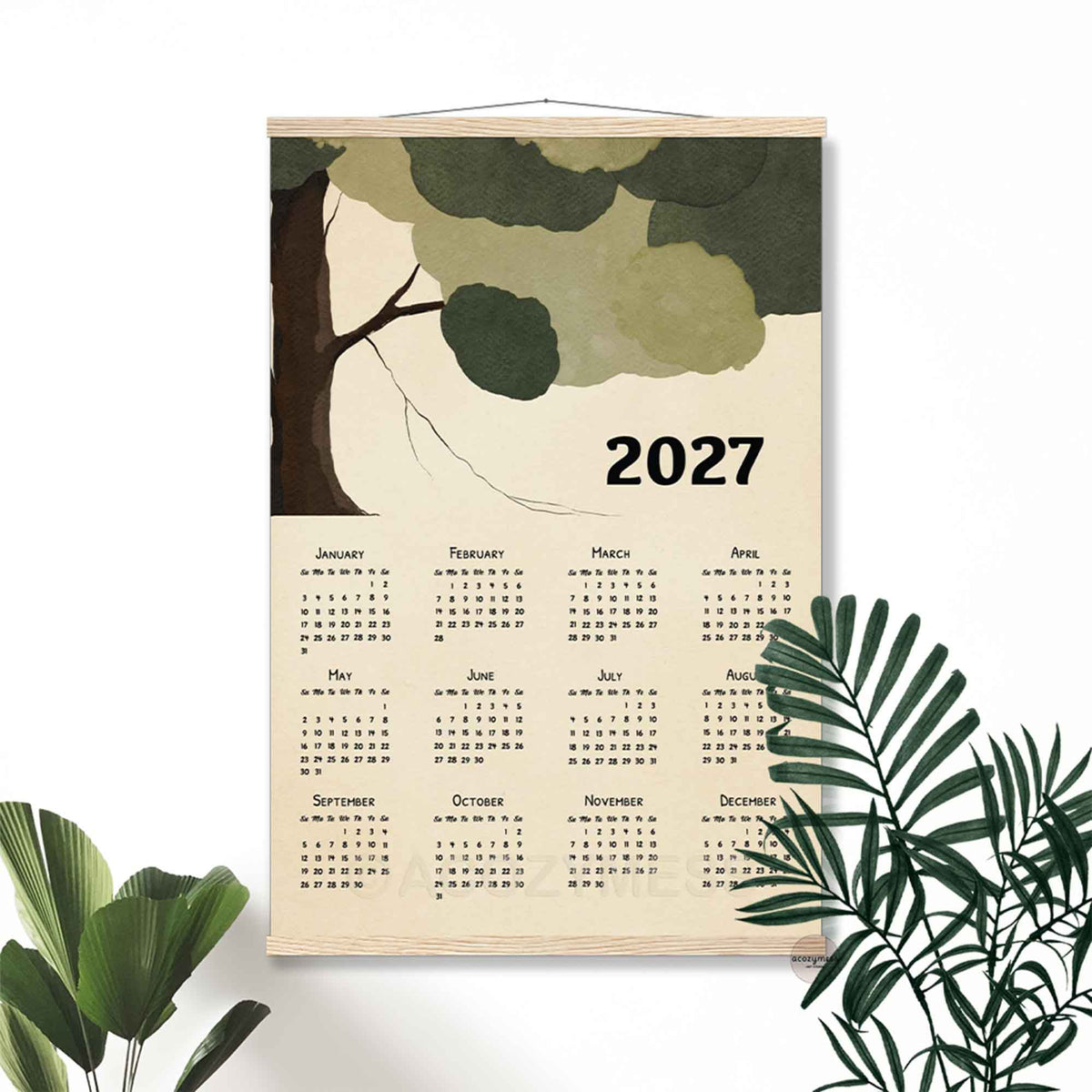 2027 tree canopy calendar print in a light wood hanger frame on a white wall with palm leaves