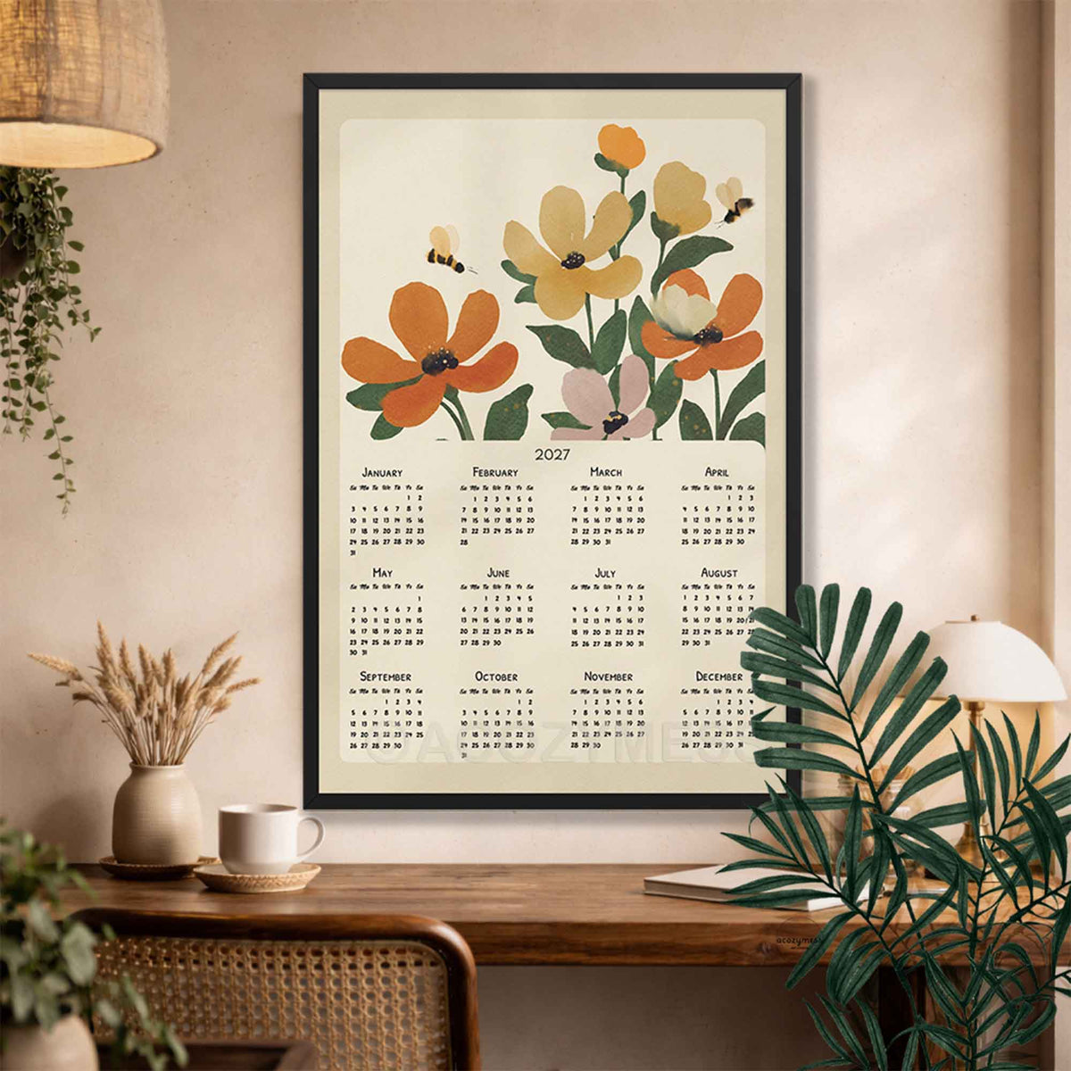 Black framed 2027 botanical floral calendar above a desk with a rattan chair, dried grasses and palm leaves