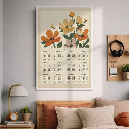 White framed 2027 orange floral wall calendar above a bed with pillows and a wooden pegboard