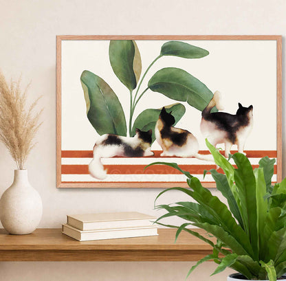 Framed artwork of three cats on a striped background with plants 