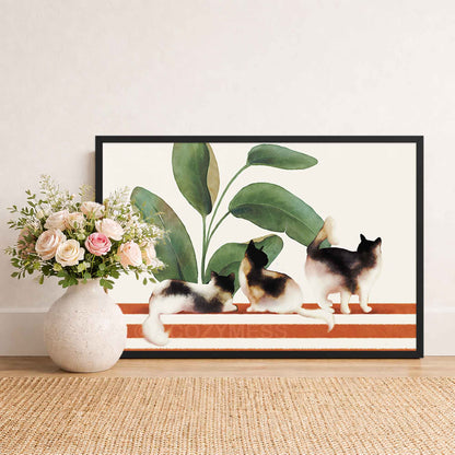 Framed artwork of three cats and a plant on a striped background, placed on a wooden floor with a vase of flowers beside it.
