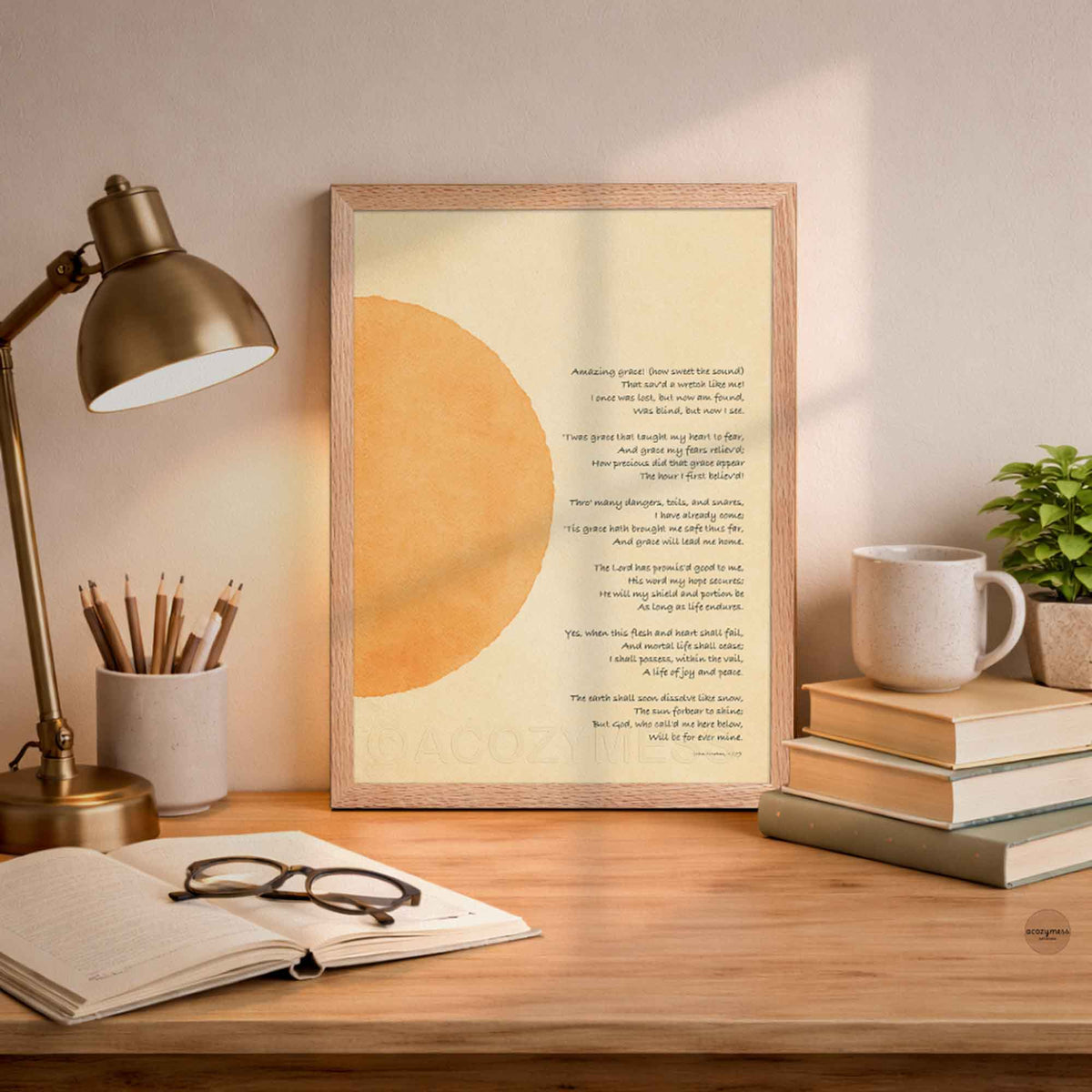 A framed art print featuring a minimalist design with a large beige circle on a cream background and a christian hymn  printed below, styled on a wooden desk.