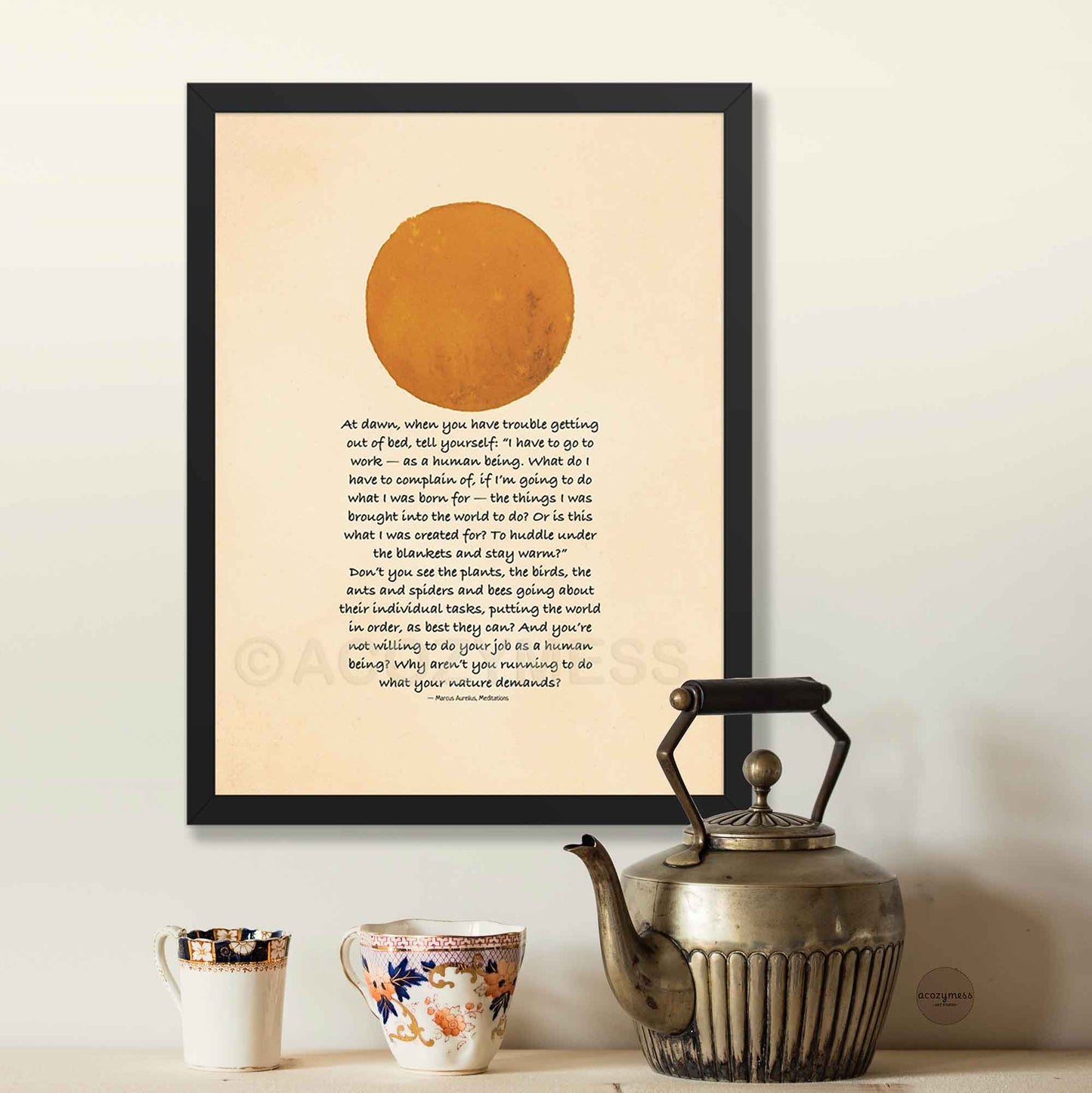 Framed artwork with a sun illustration and Inspirational quote on a wall above a teapot and mugs.