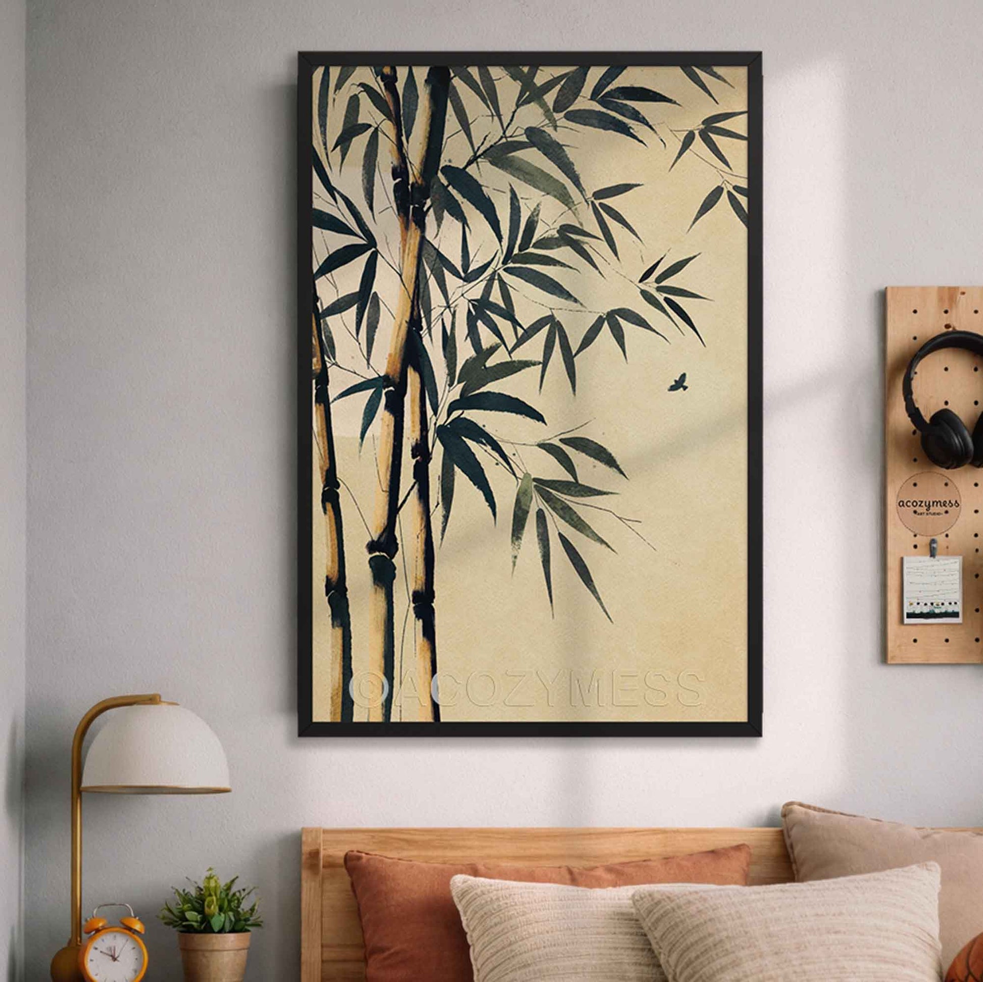 Framed artwork of bamboo leaves on a wall above a bed in a bedroom.