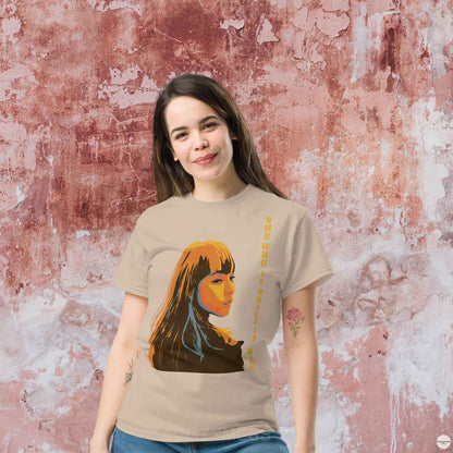 A woman wearing sand t-shirt featuring an illustration of a woman and the quote, She who is brave is free, inspired by Seneca. The design reflects strength and elegance, making it perfect for casual and versatile wear.