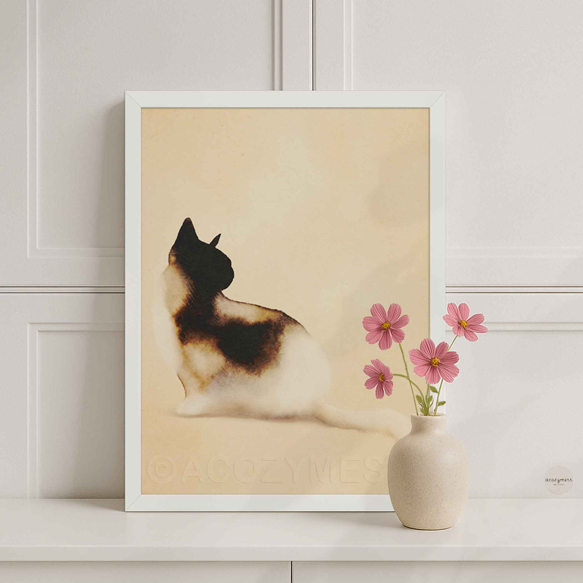 White framed minimalist cat poster on a white console with a pink flower vase in a bright room