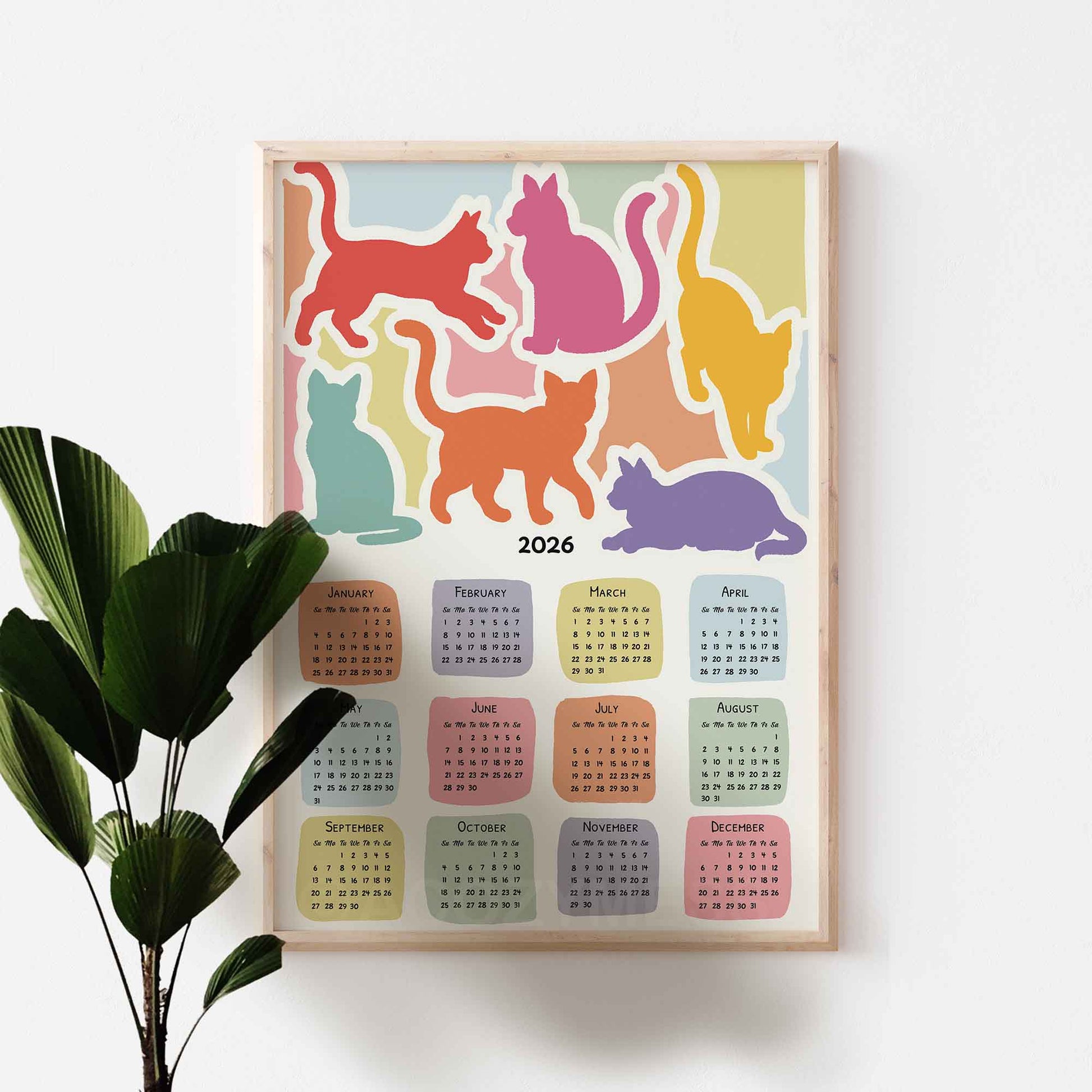 2026 calendar with colorful cat illustrations on a white wall.