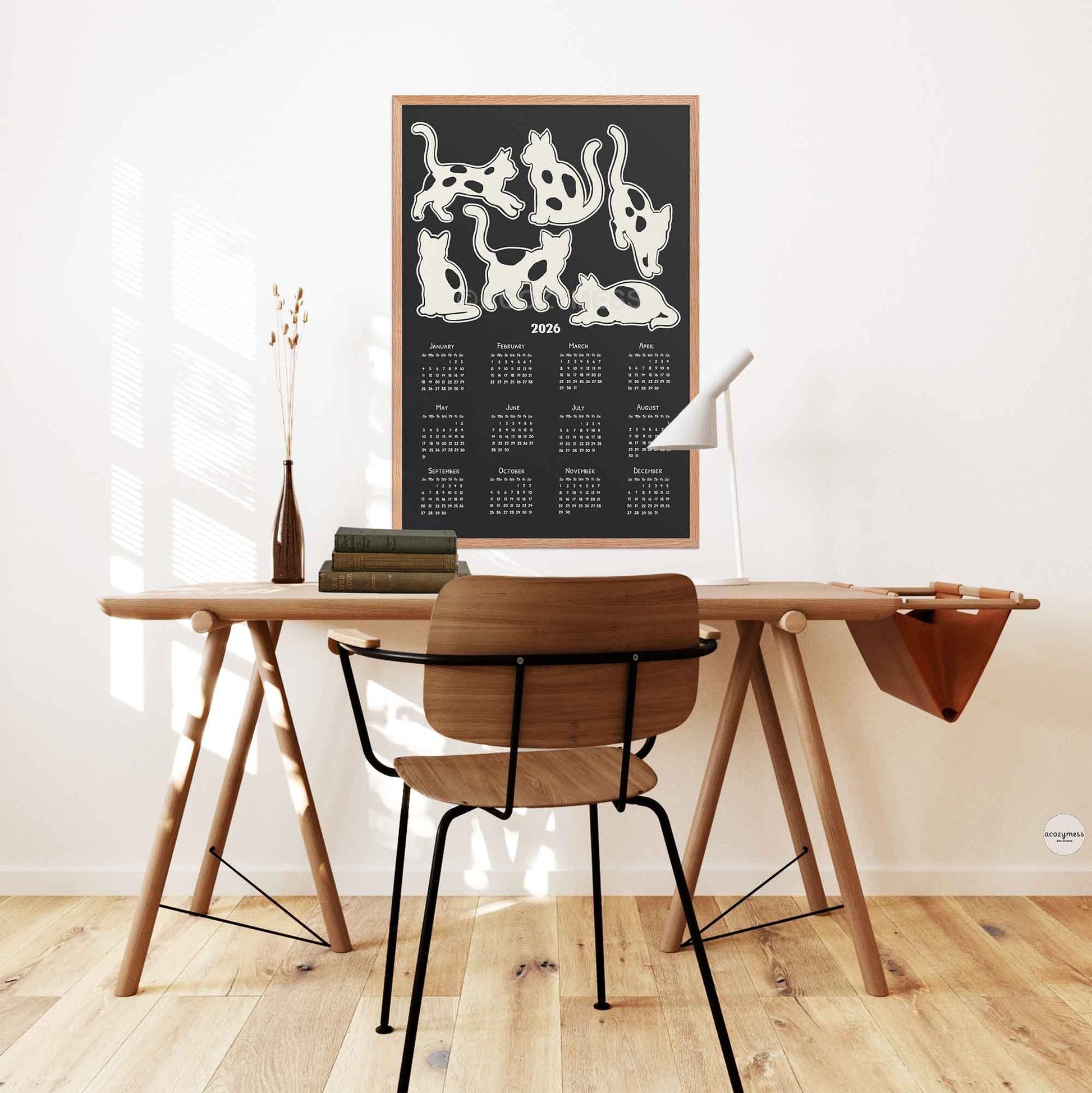 2026  yearly calendar with cute cats illustration in black and white hung over a desk
