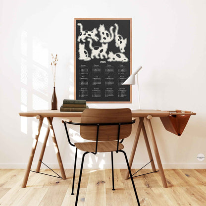 2026  yearly calendar with cute cats illustration in black and white hung over a desk