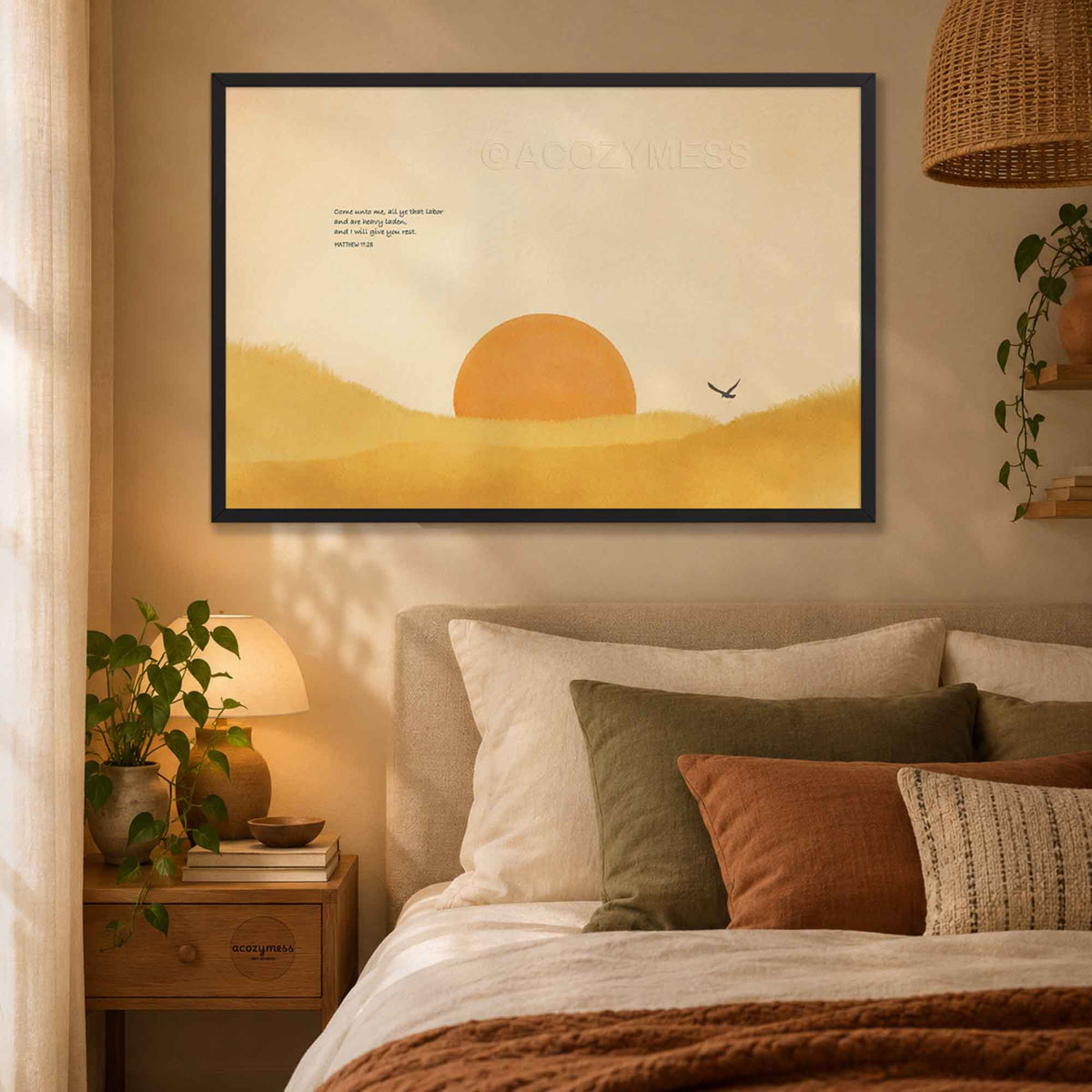 Black framed Come Unto Me Matthew 11:28 Bible verse poster with a golden sun over watercolor hills above a bed with cozy pillows, a bedside lamp and a rattan pendant