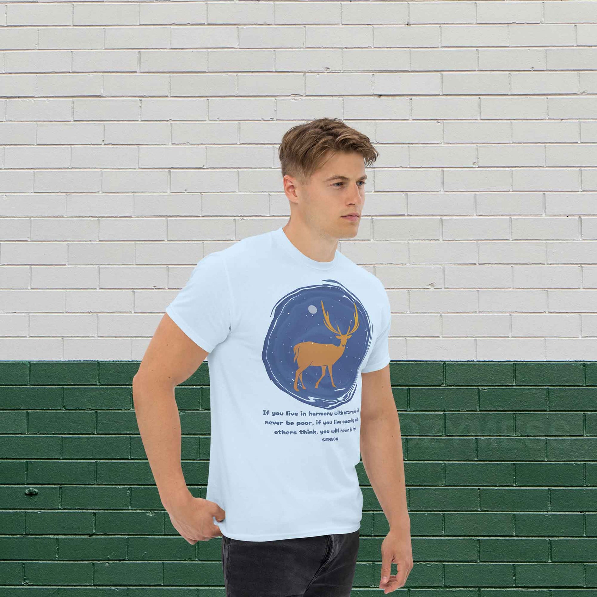  A light blue T-shirt featuring a minimalist design of a majestic deer standing under a starry night sky, accompanied by a quote from Seneca: If you live in harmony with nature, you will never be poor. If you live according to what others think, you will never be rich.