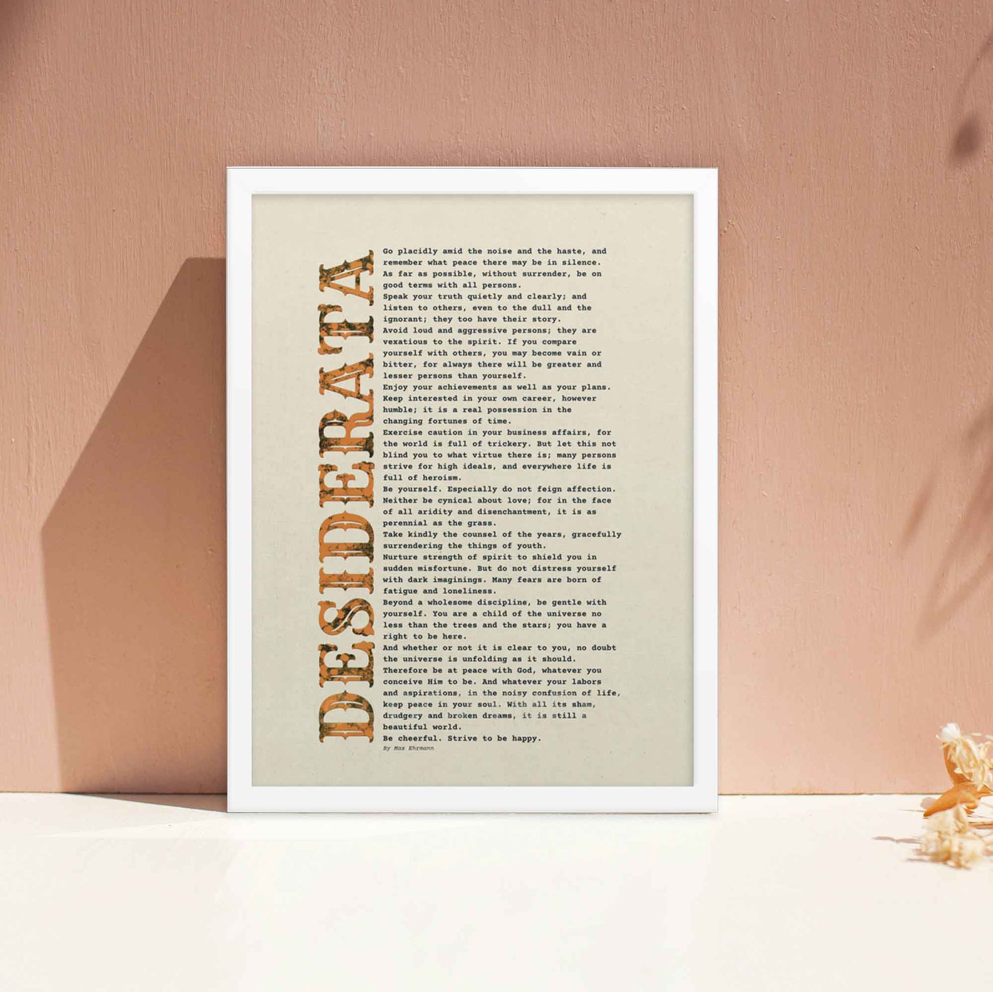 desiderata Poem Poster black and orange on beige, displayed in white frame.