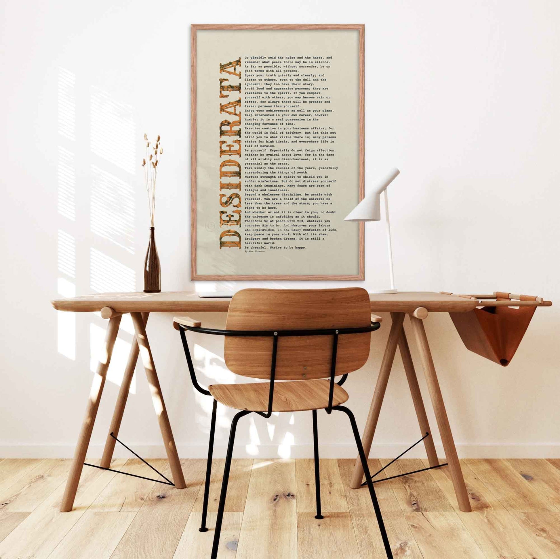 desiderata Poem Poster black and orange on beige, displayed in oakwood frame on a desk wall.