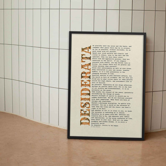 desiderata Poem Poster black and orange on beige, displayed in black frame.