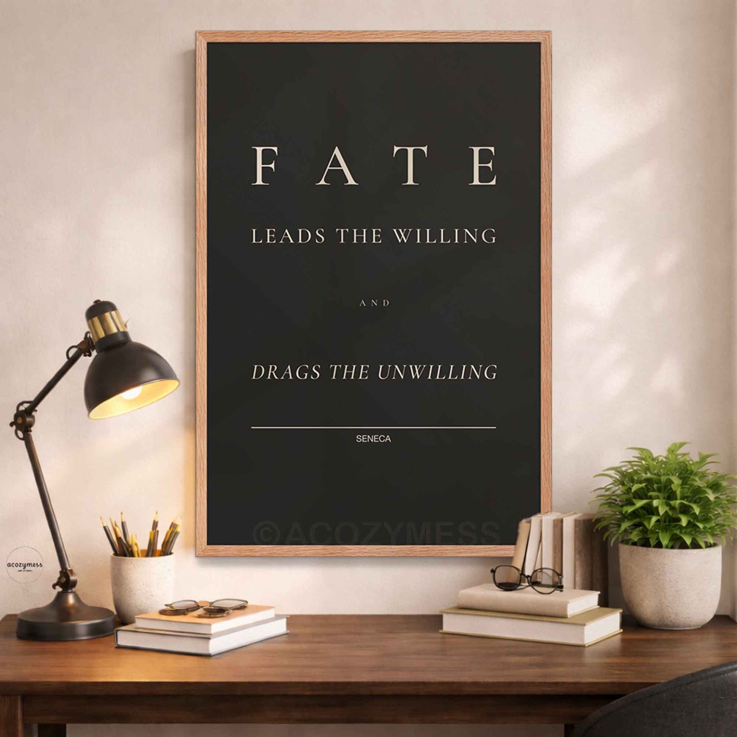 Framed poster with 'Fate leads the willing and drags the unwilling' quote by Seneca on a desk with decor items.