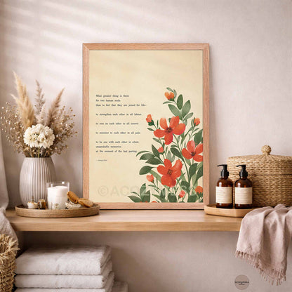 A framed botanical art print with a quote is displayed on a wooden shelf in a styled bathroom setting.