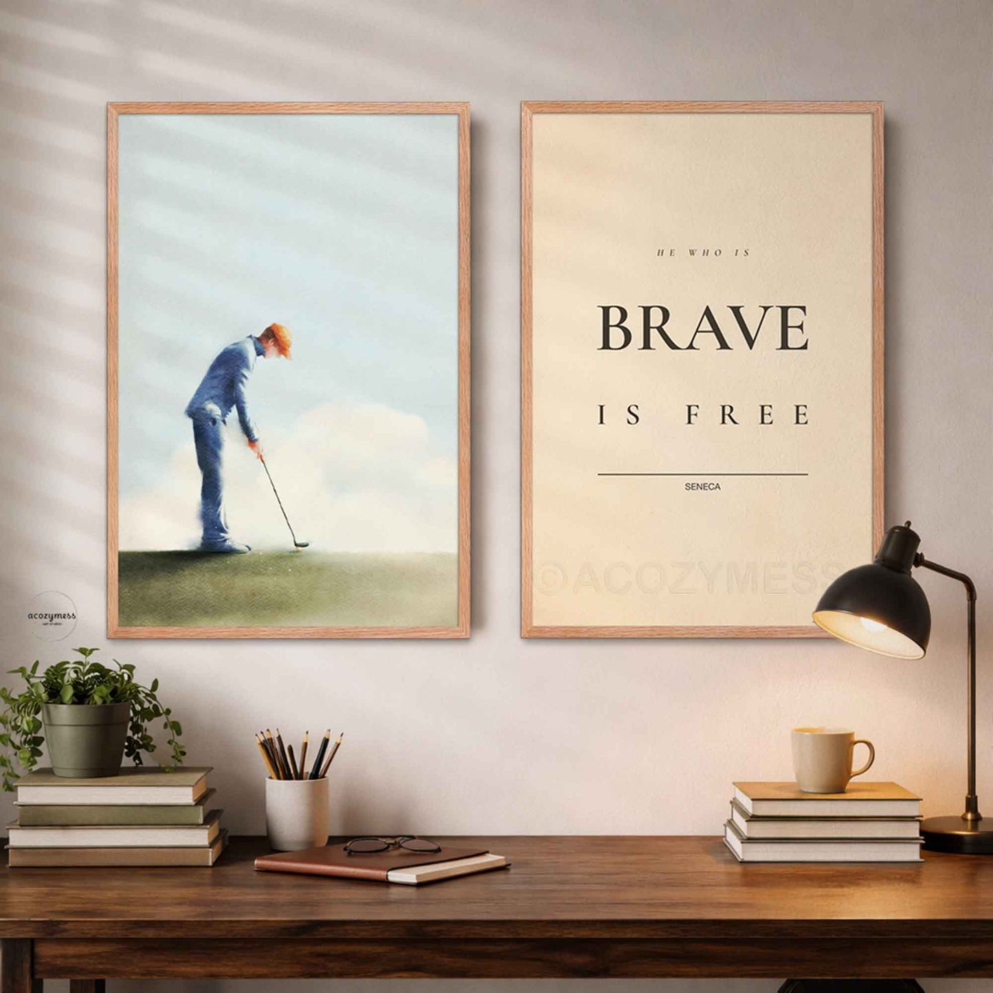 Two framed prints on a wall above a desk with books and a lamp.