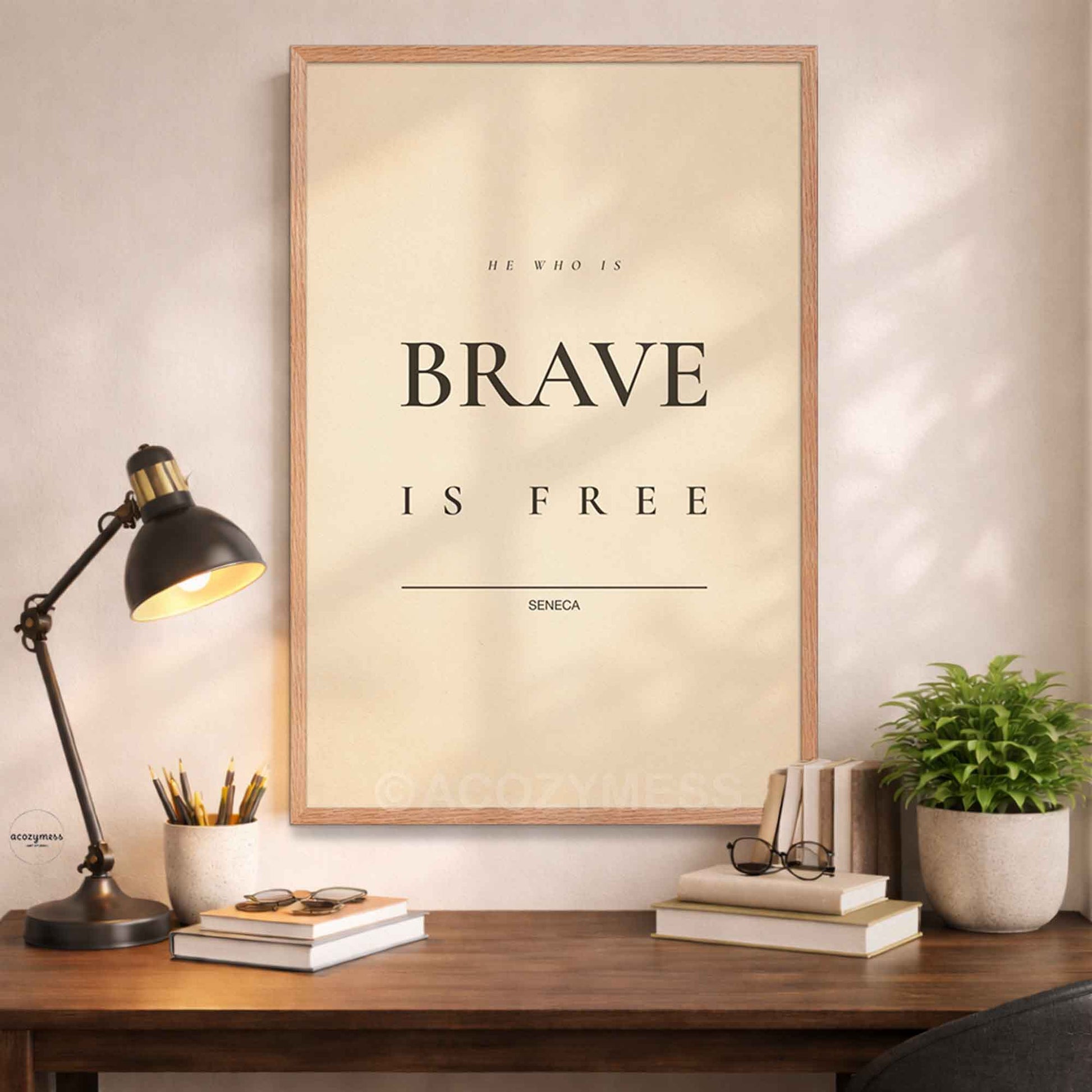 Framed poster with 'He who is brave is free' quote by Seneca on a wall above a desk with decor items.