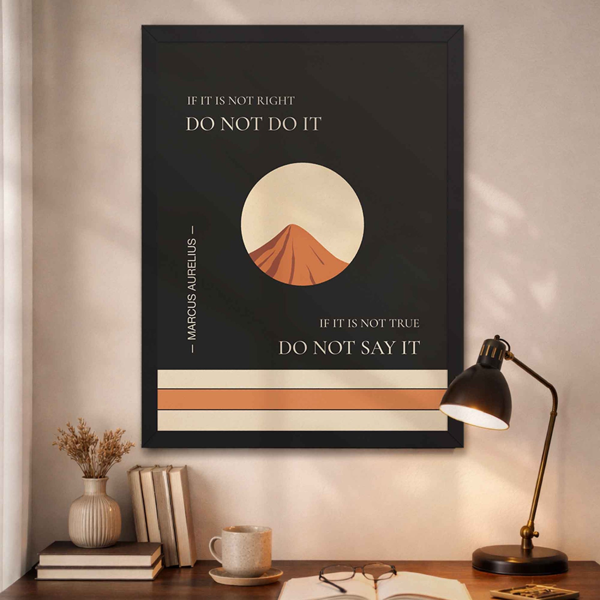 Marcus Aurelius quote wall art in black frame with mountain illustration above a desk with books and a lamp.