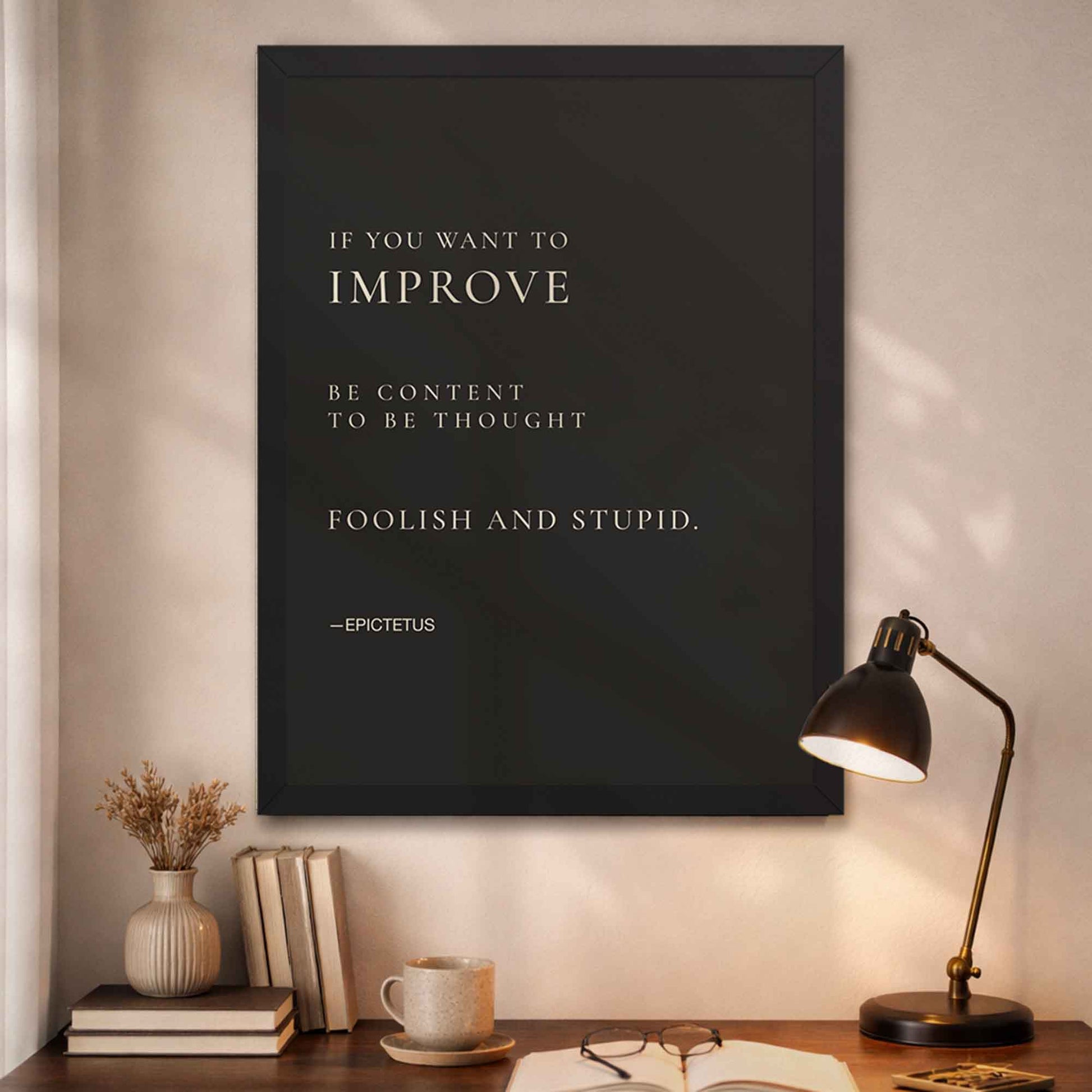 Framed Epictetus quote on a wall above a desk.
