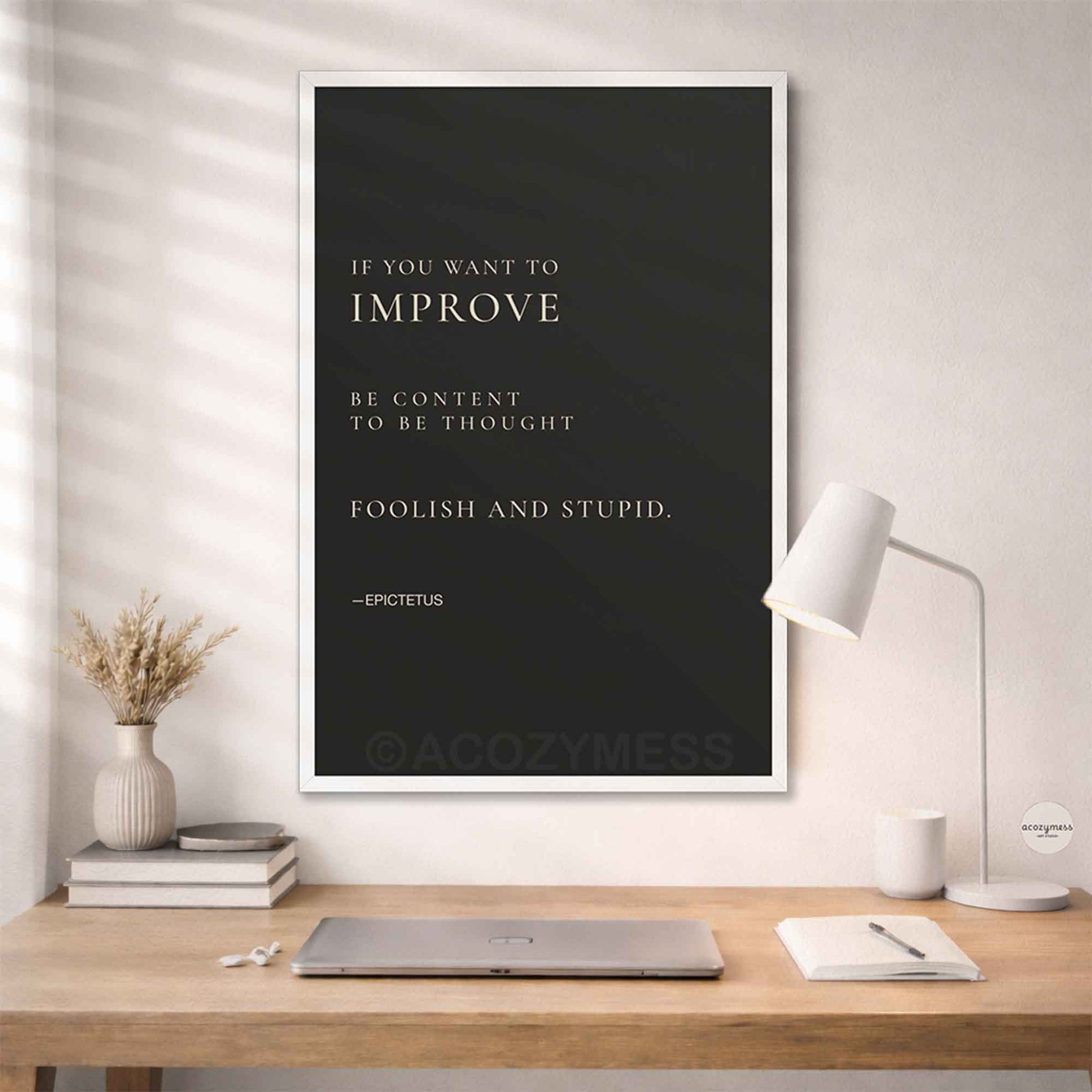 White Framed quote by Epictetus on a wall above a desk.